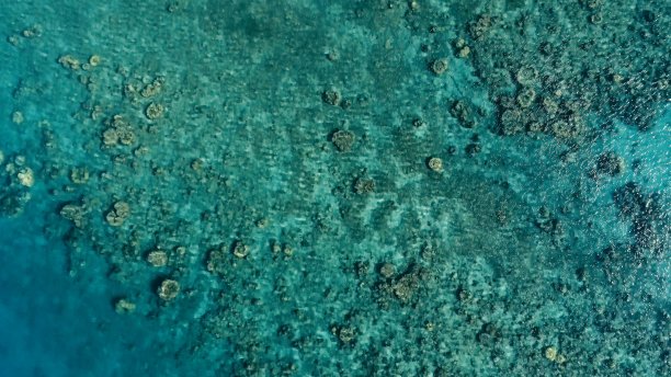 在一个偏远的热带孤岛上，一艘小渔船进入一个海洋锚地，在清澈湛蓝的海水中，珊瑚礁旁边的一个海峡图片下载