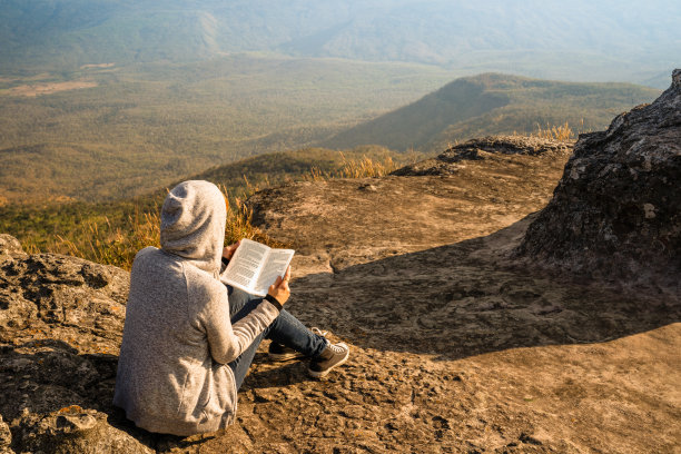 一位妇女坐着看书，望着窗外美丽的自然景色图片下载