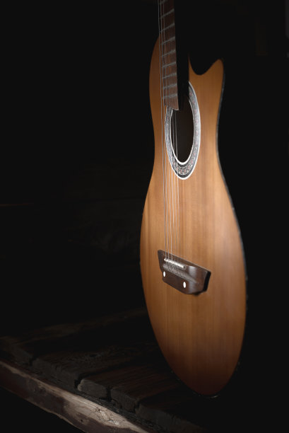 一把旧的棕色吉他的一部分，有弦，背景是深色的木头。有选择性的重点图片下载