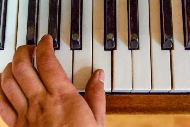 孩子的手放在闪亮的钢琴键上。俯视图图片下载