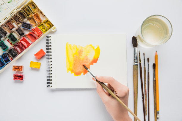 俯视图的女性手绘在相册与水彩颜料和画笔图片下载