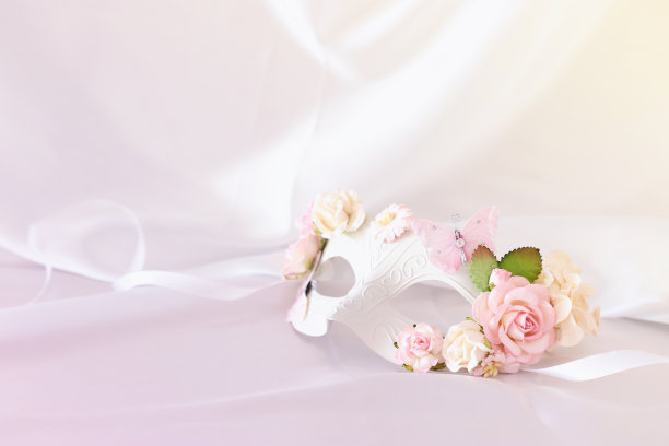 照片优雅和精致的白色威尼斯面具与粉红色的花卉装饰在丝绸的背景。图片下载