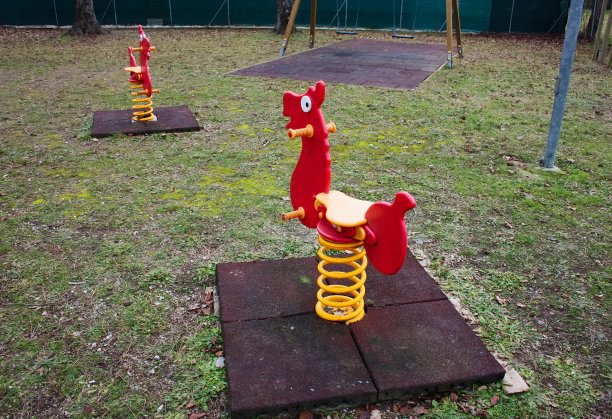 儿童摇滚游戏。红色的秋千像小马一样。废弃的操场。图片下载