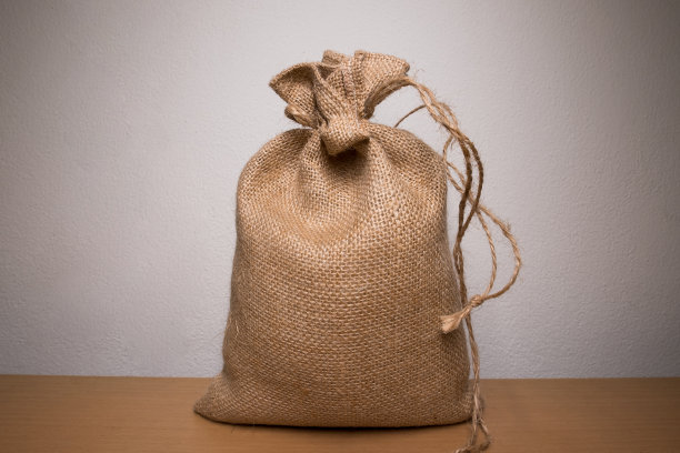 装有茉莉花米的袋子放在白色墙壁背景前面的木桌上，上面有灯光图片下载