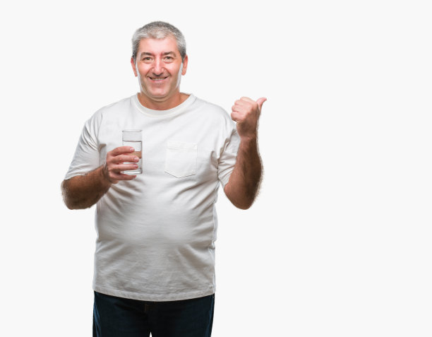 英俊的资深男子喝了一杯水在孤立的背景指向和显示与拇指向上到一边与幸福的脸微笑图片下载