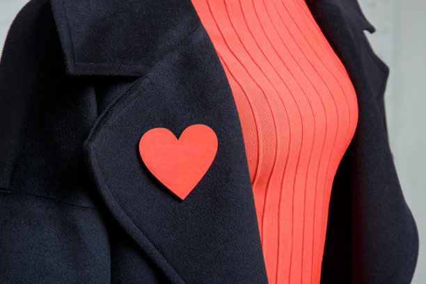 女性服装的细节。一枚心形胸针别在一件黑色外套上图片下载