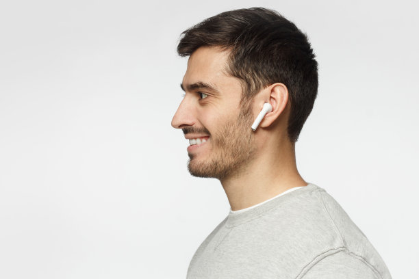侧面的微笑的年轻人听音乐或收音机，使用现代无线耳机图片下载