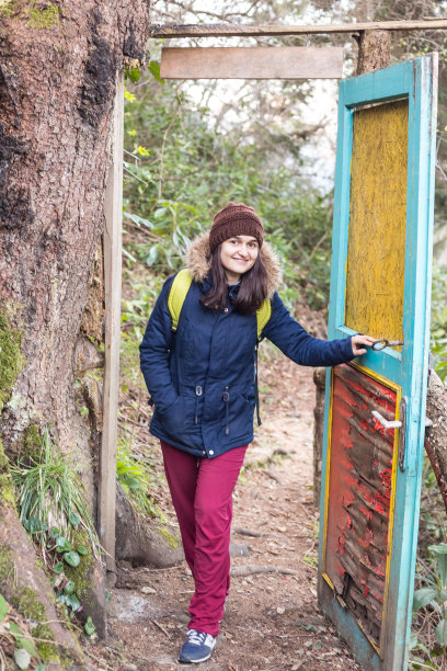 年轻快乐的女人在森林里打开被毁坏的木门图片下载