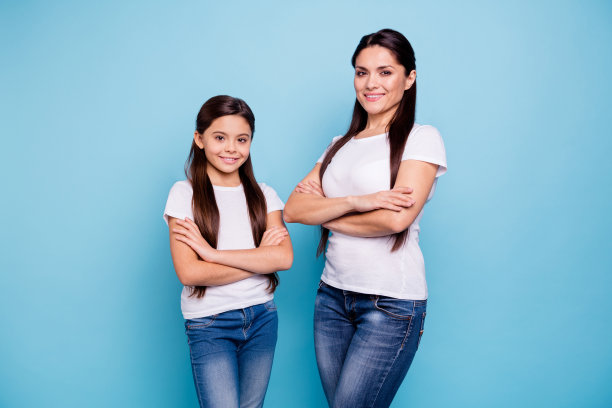近距离的照片漂亮的两个人棕色头发的妈妈，小的女儿双臂交叉，自信地站在对面准备赢赢家家庭游戏胜利，穿t恤孤立亮蓝色的背景图片下载