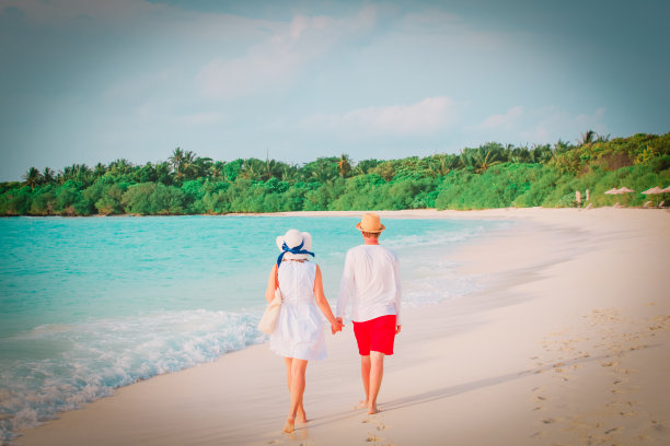 一对幸福的情侣在海滩上散步，一家人在热带度假图片下载