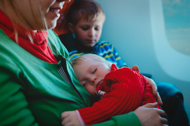 母亲带着熟睡的婴儿和儿子乘飞机旅行图片下载