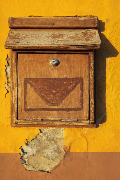 黄色的墙上挂着一个木制的旧信箱图片下载