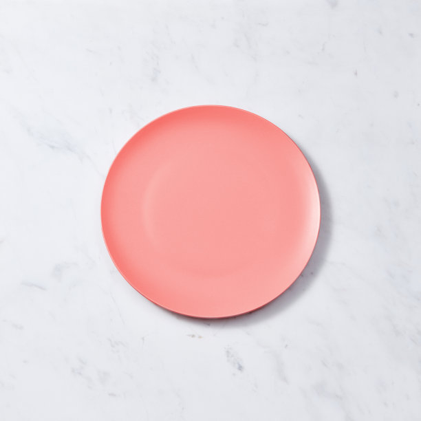 在灰色大理石桌子上放置文字，用2019年最受欢迎的活珊瑚色手工制作的瓷空盘子。平躺图片下载