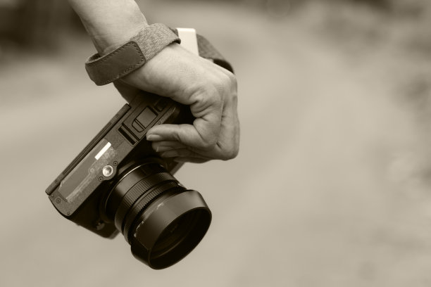 女人手持数码相机在黑色的色调与拷贝空间。图片下载