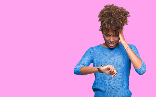 美丽年轻的非洲裔美国女子过孤立的背景看着手表时间着急，害怕迟到图片下载