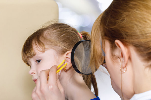 儿科医生在治疗一个小孩的时候正在检查她的耳朵。图片下载