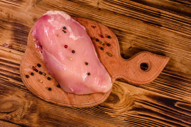 木桌上的切菜板上放着生鸡柳和各种香料。俯视图图片下载