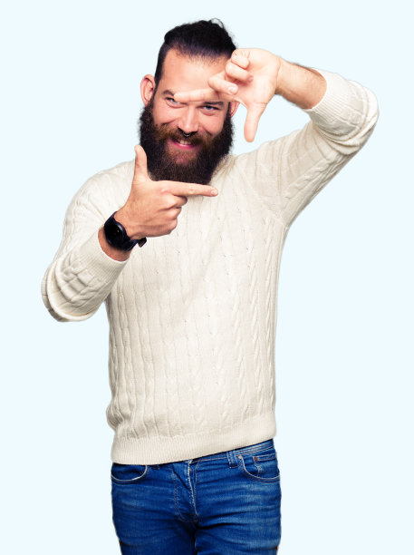 年轻的潮人穿着冬季毛衣微笑做框架与手和手指与快乐的脸。创意和摄影概念。图片下载