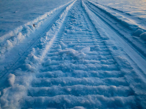 雪地摩托上的步道穿过远处森林的雪堆。图片下载