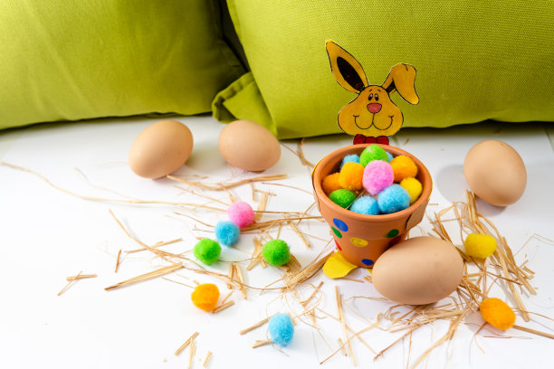 不同颜色的复活节彩蛋放在桌子上，旁边是绿色和兔子。图片下载
