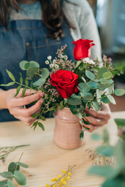 一位女花商在木桌上做了一束红玫瑰图片下载