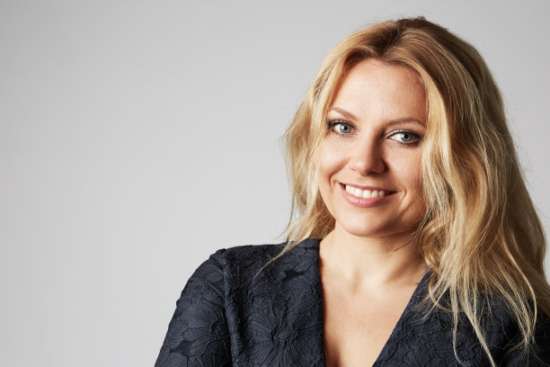 时尚照片的一个美丽的金发女人在一个漂亮的裙子摆出灰色的空白背景。拍摄时尚照片。复制粘贴的空间。图片下载