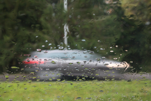 雨滴落在汽车玻璃上，注意雨滴。可以看到街道和正在行驶的汽车。长时间曝光的照片。图片下载