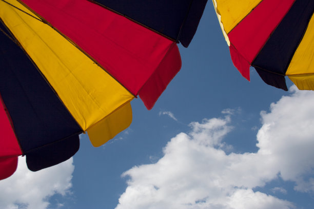 蓝色的天空下挂着松软的云朵，两把亮闪闪的雨伞图片下载