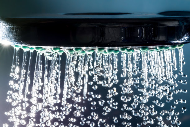 现代淋浴与水流和阳光散景特写微距在黑暗的背景图片下载