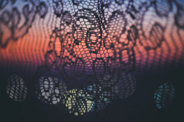 令人惊奇的浪漫日落在窗户后面的轮廓薄纱纹理。美妙的粉红色、紫色、蓝色的黎明天空透过窗户的图案窗帘。美丽日出的舒适背景。副本的空间。图片下载