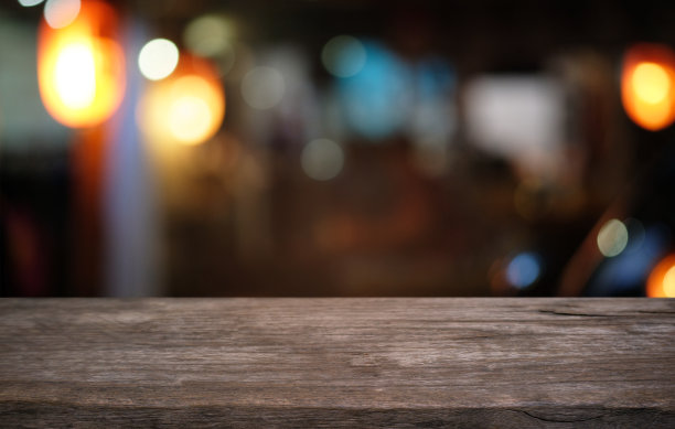 空荡荡的深色木桌前面抽象模糊的散景餐厅背景。可用于展示或蒙太奇您的产品。模拟空间。图片下载