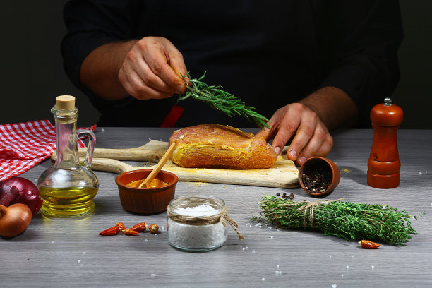 厨师用迷迭香在厨房烤盘上按经典食谱烹调肉类。在深色背景上烹饪文字或设计，水平照片图片下载