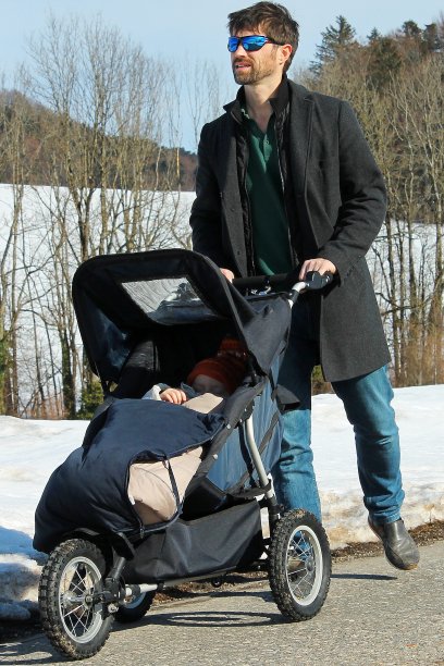 父亲在雪地里推着婴儿车图片下载