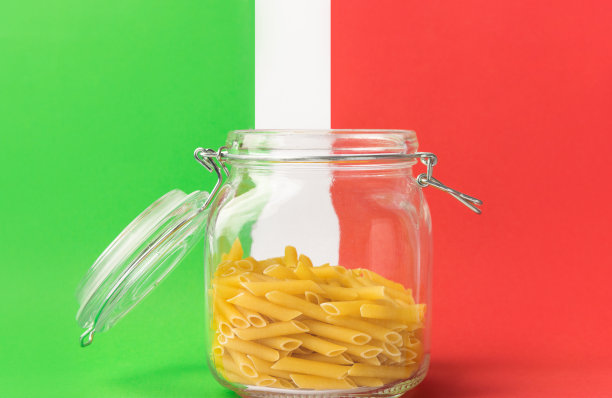 生通心粉在玻璃水晶储存罐中，盖子打开，白色，绿色，红色背景模仿国旗的颜色。意大利美食的概念。创意图像与复制空间图片下载