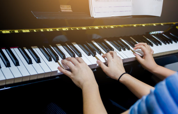有选择地聚焦于一个年轻女子用乐谱教一个男孩弹钢琴的画面。图片下载