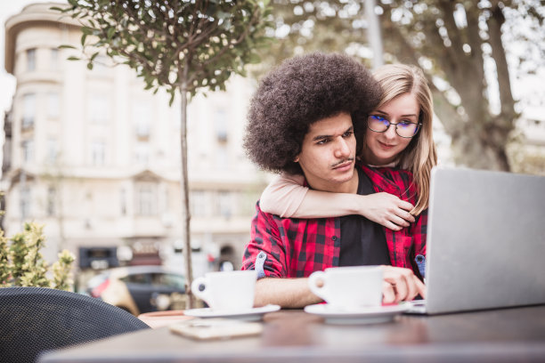 学生的生活。一对年轻的夫妇，坐在咖啡店里，用笔记本电脑浏览互联网。图片下载