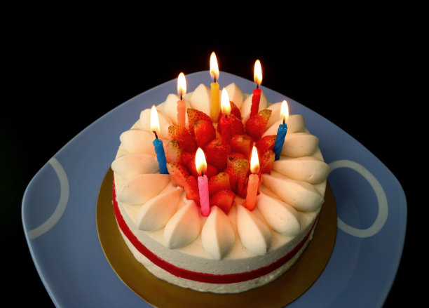 在黑暗中在草莓香草短蛋糕上点燃蜡烛图片下载