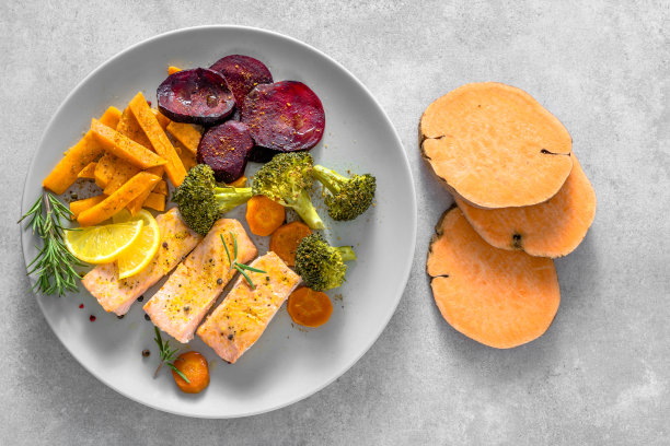 盘子里有煮熟的蔬菜和烤鲑鱼。晚餐有鱼和什锦蔬菜。图片下载