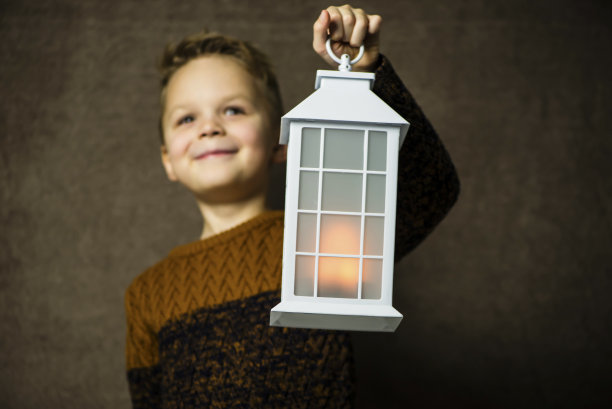 可爱的男孩拿着一盏发光的古董灯图片下载