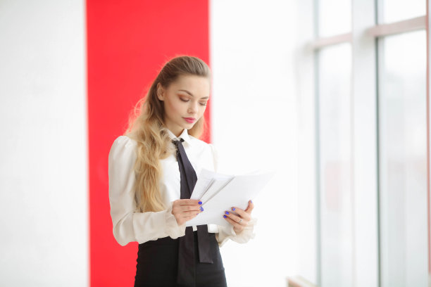 穿着白色衣服的时尚女孩拿着一个文件夹，看着相机图片下载