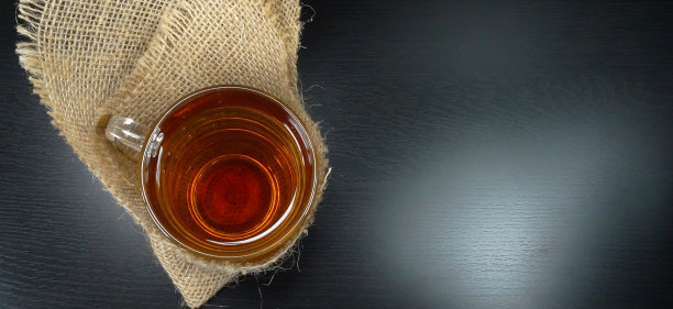 在一个冬天的一天，用粗麻袋/粗麻袋在一个黑色的背景/喝茶时间的热茶杯玻璃杯图片下载