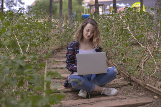 微笑的年轻女子在公园使用笔记本电脑的肖像图片下载