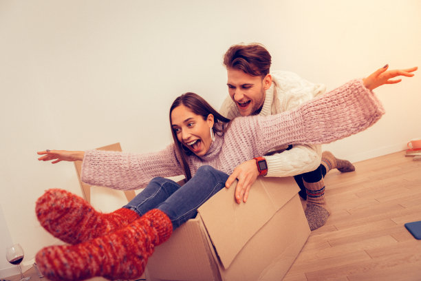 黑头发的妻子穿着牛仔裤和毛衣坐在空盒子里图片下载