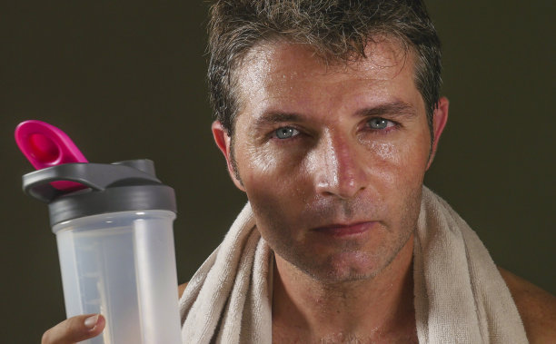 头和肩膀的肖像年轻的吸引力和英俊的运动员出汗后健身房锻炼艰苦看起来出汗和挑衅与毛巾在他的脖子上喝水瓶图片下载