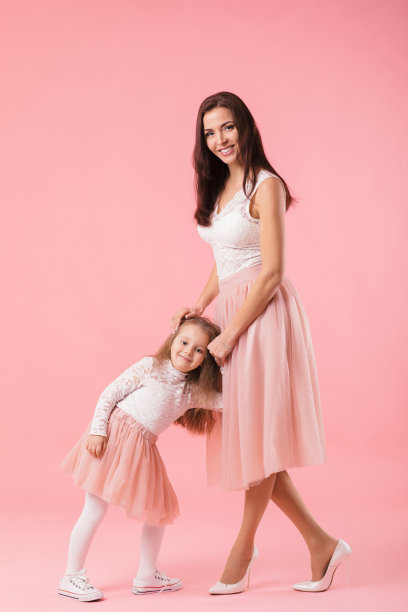 迷人的母亲和微笑的女儿在粉红色的背景图片下载