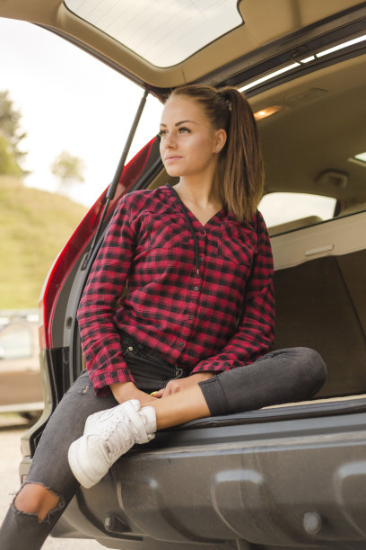 漂亮的年轻女子在红色衬衫和牛仔裤摆姿势户外图片下载