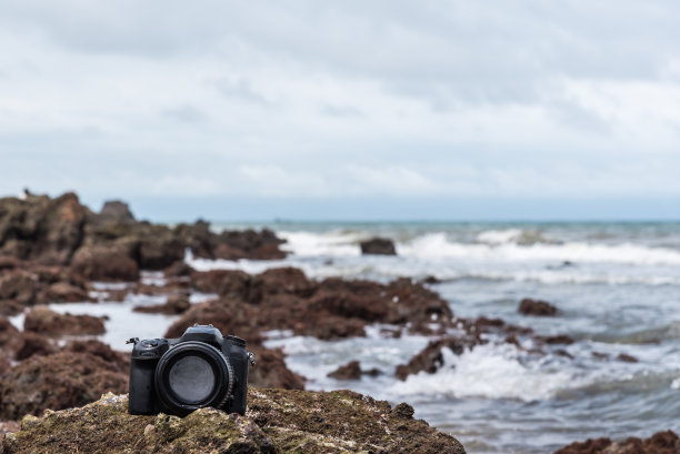 石滩上的单反相机被海浪打湿图片下载