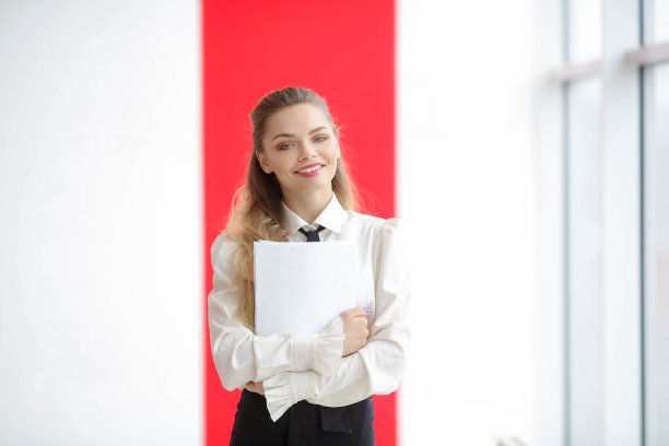 穿着白色衣服的时尚女孩拿着一个文件夹，看着相机图片下载