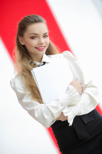 穿着白色衣服的时尚女孩拿着一个文件夹，看着相机图片下载