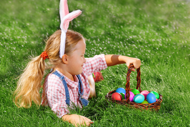 可爱的小女孩抱着篮子在公园的绿草地上。E图片下载